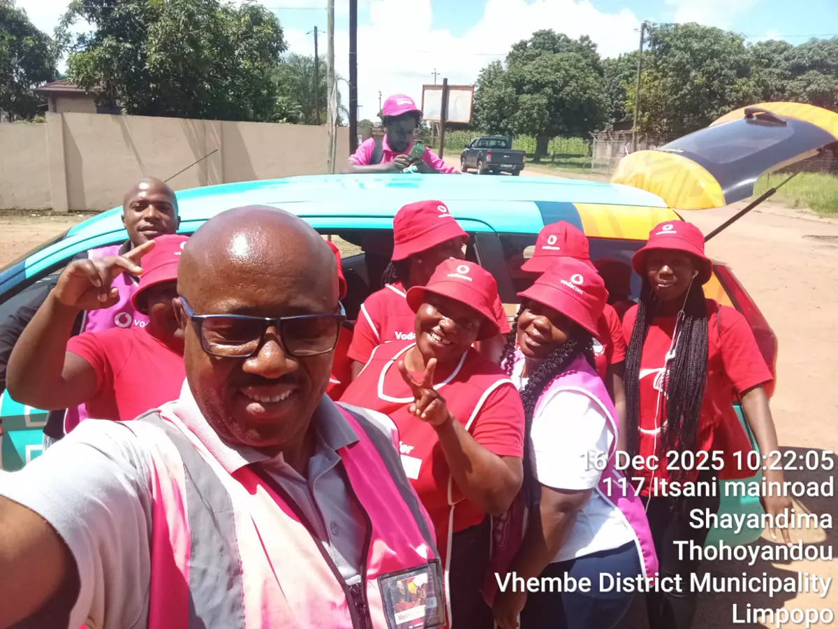 Group wearing red apparel and bucket hats taking a selfie next to a branded car