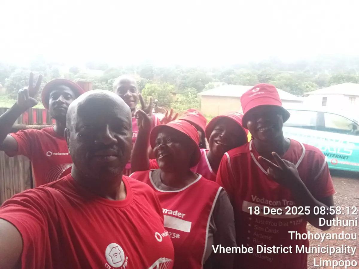 Group in red promotional shirts and hats taking a selfie outdoors